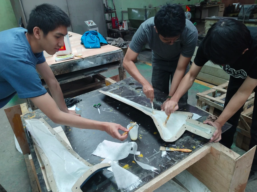 Laminating fiberglass into the blade molds in the workshop